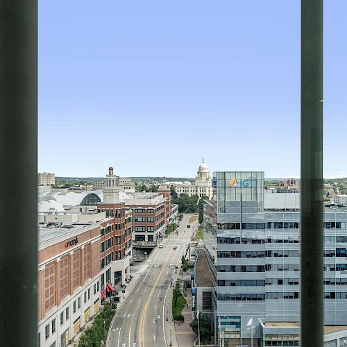 A cityscape with a prominent dome building in the distance, framed by two vertical dark poles, showing streets and buildings on a clear day.