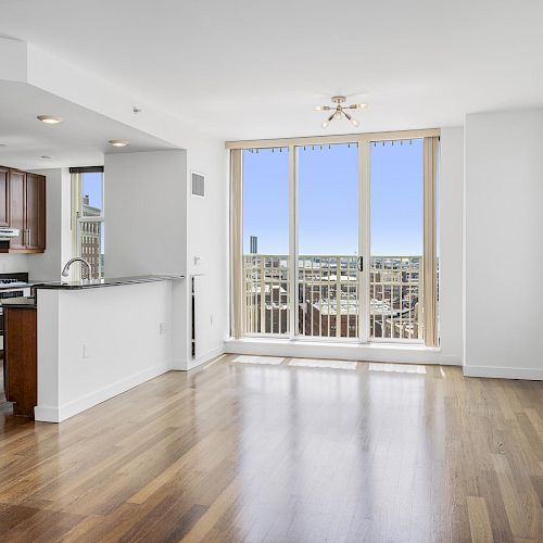 Bright and modern apartment with hardwood floors, an open-concept kitchen, large windows, and a city view balcony ending the sentence.